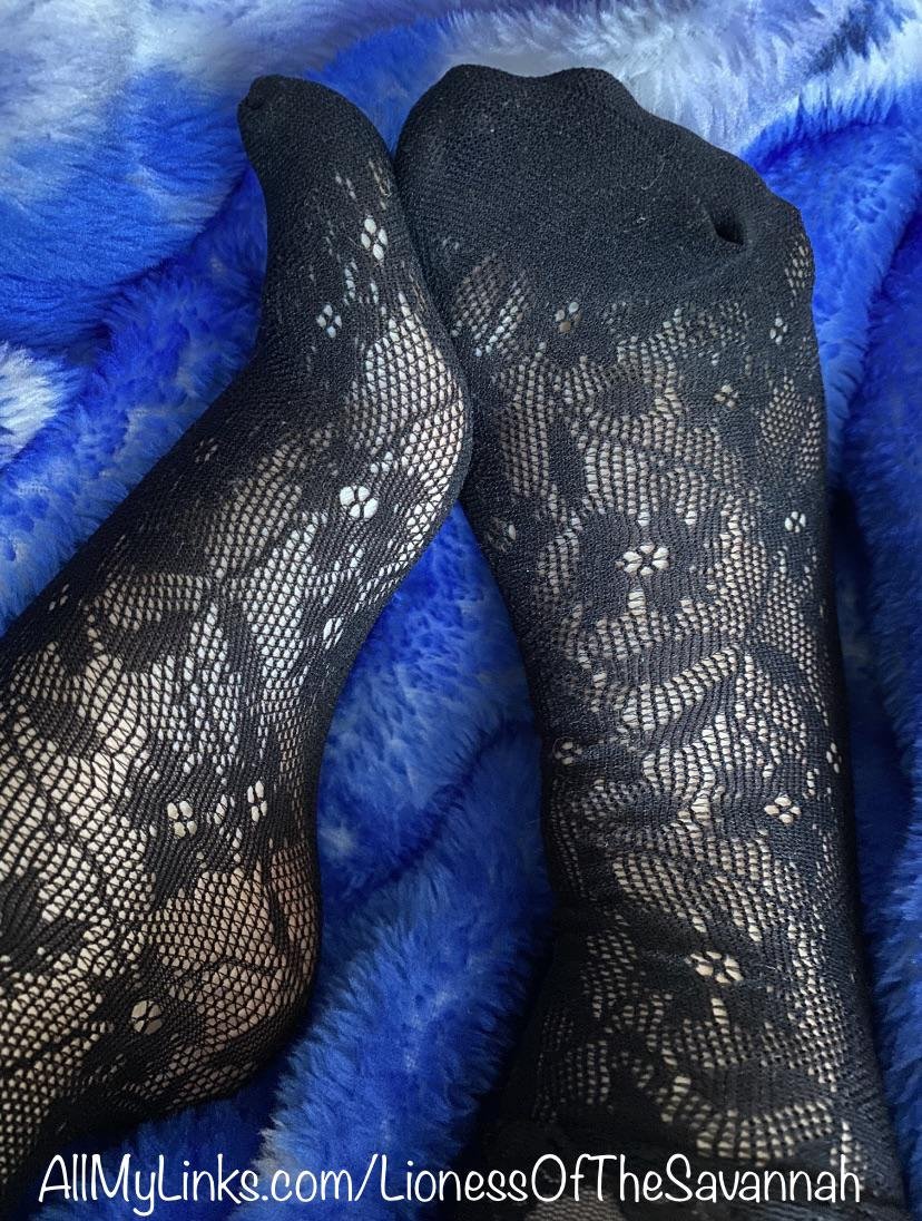 Feet in black floral lace tights with a small hole at the toe on a bright blue fluffy blanket