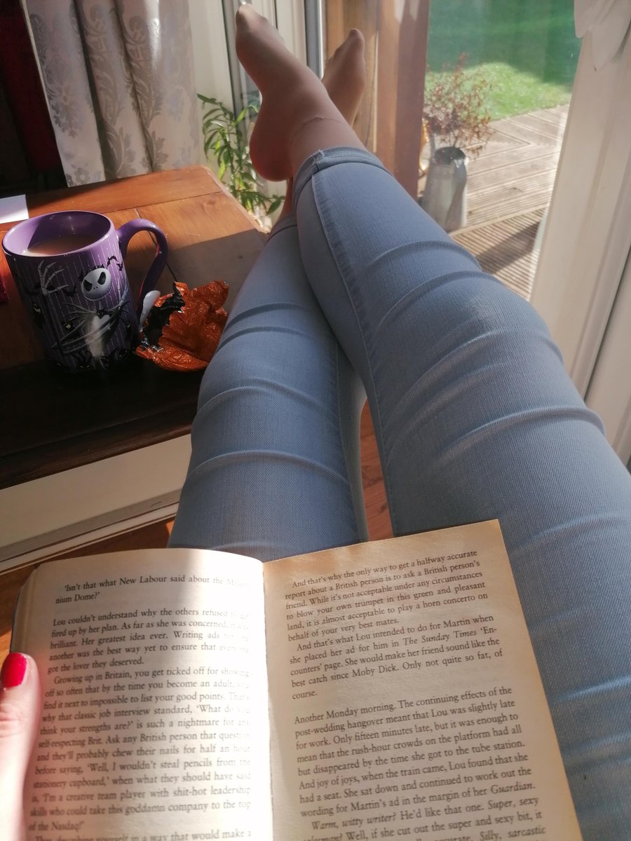 Woman lying and reading with her extended legs crossed in light blue footless tights