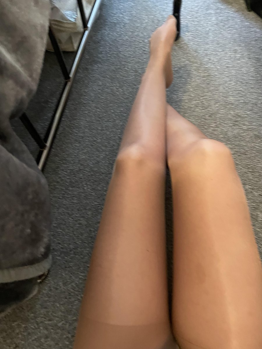 Long legs in glossy tan sheer pantyhose lying on a grey carpet