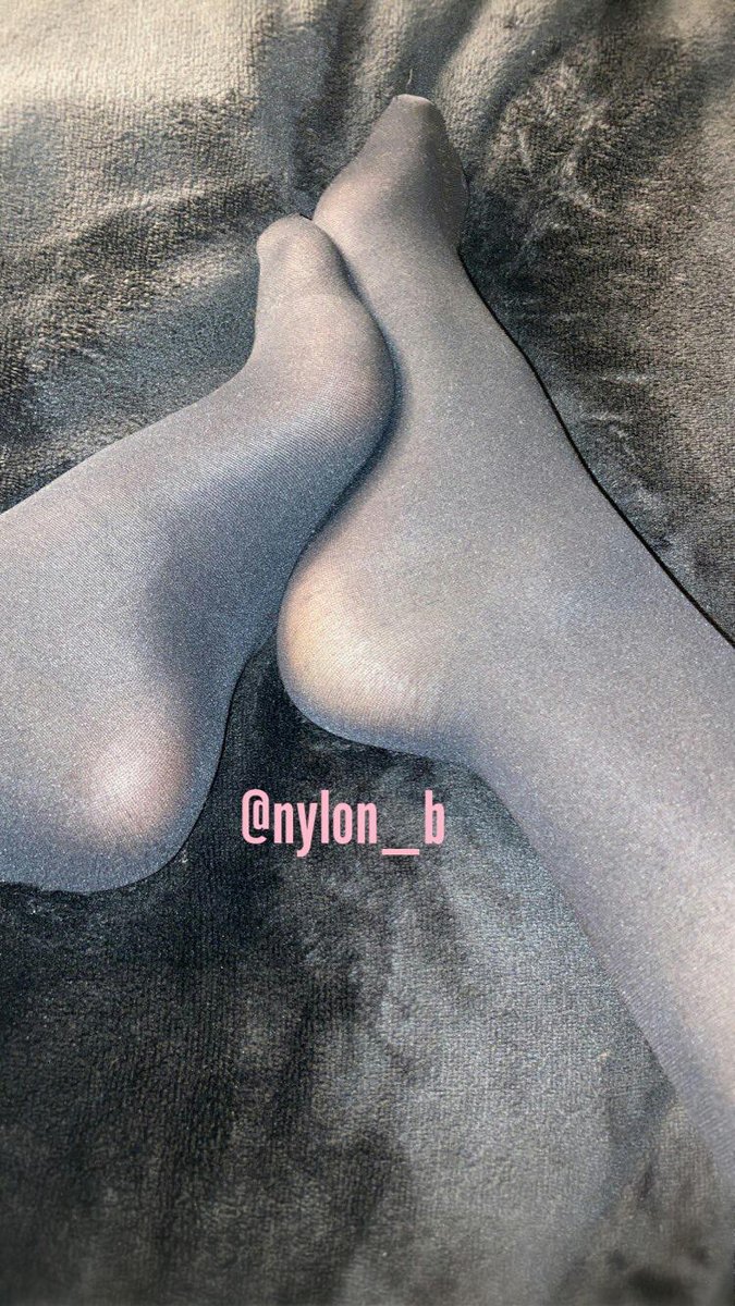 Feet crossed in sheer grey pantyhose on a dark fluffy blanket