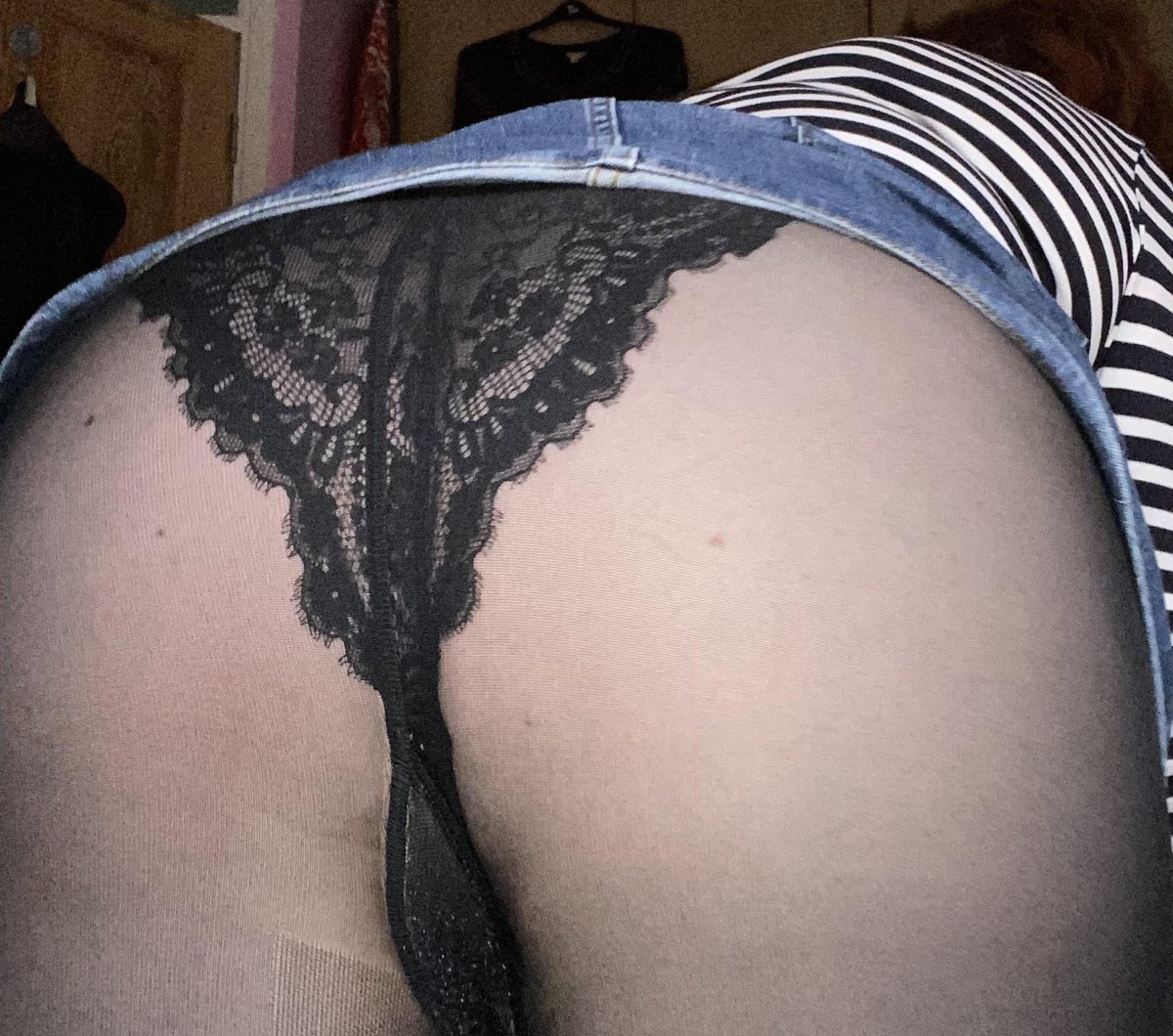 Close-up from behind in a blue denim skirt with black lace panties over sheer black pantyhose